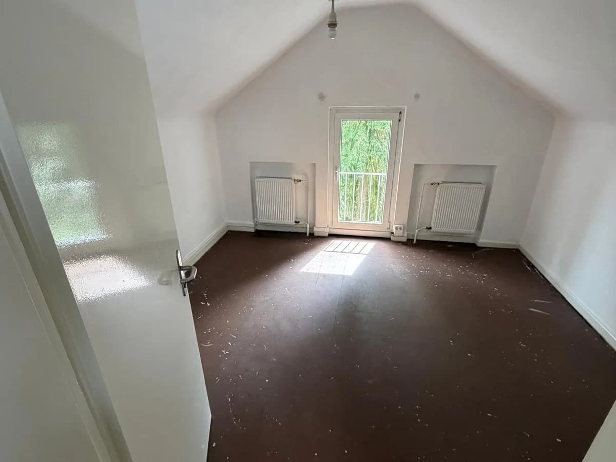 Leerer Raum mit altem Bodenbelag unter der Dachschräge