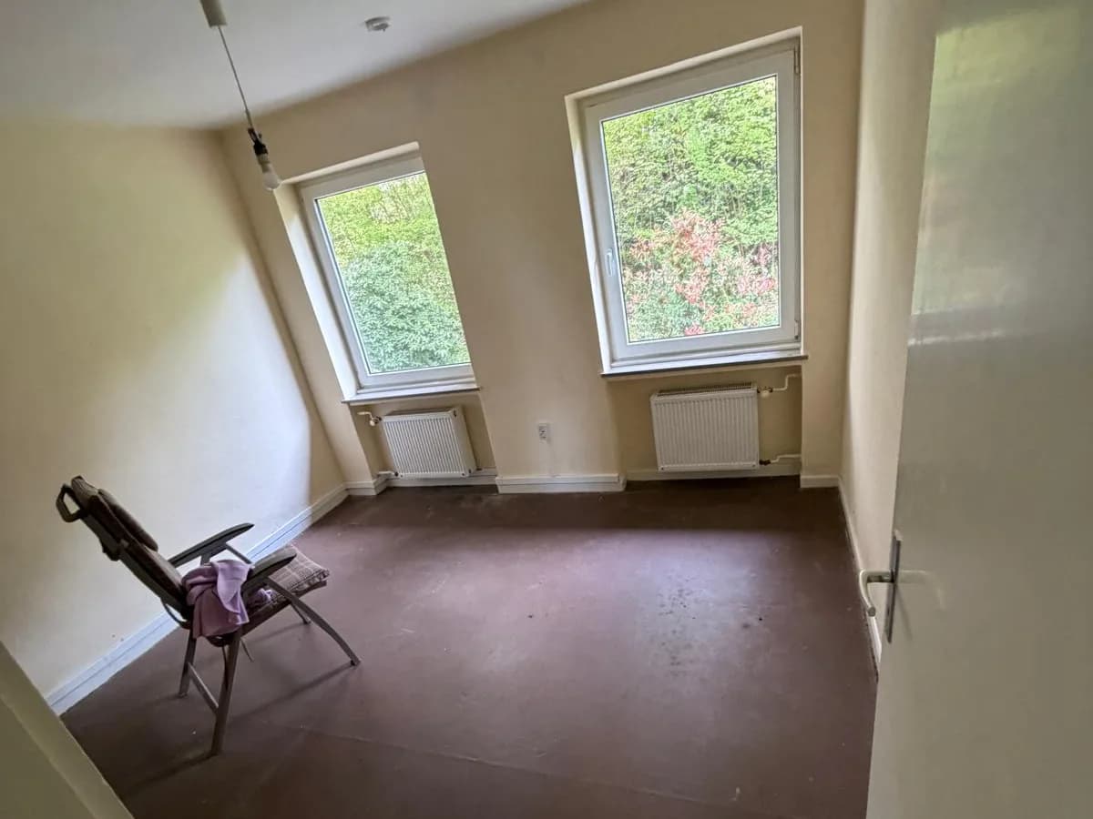 Zimmer mit altem PVC-Belag und zwei Fenstern